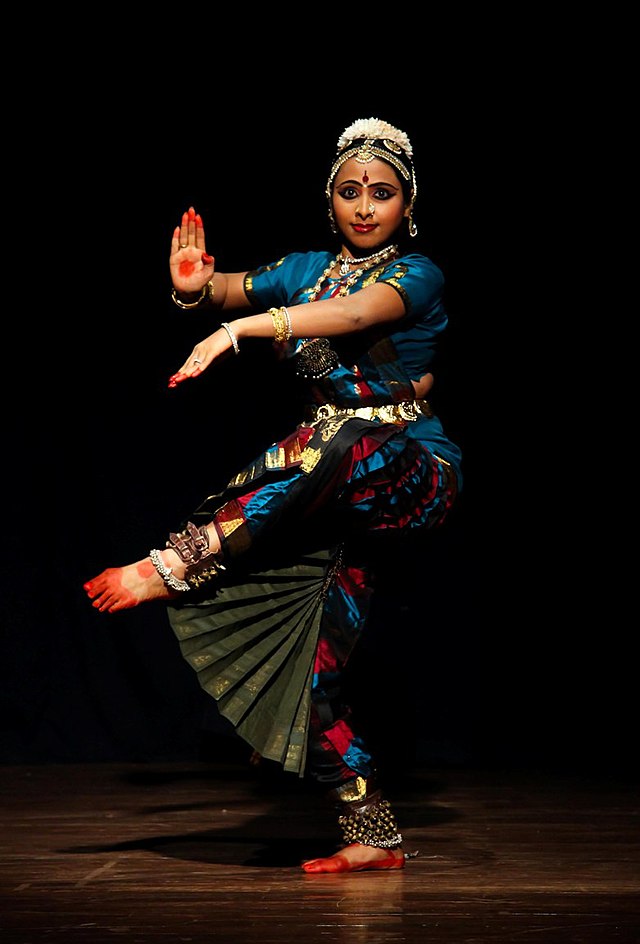 Bharatanatyam dancer at Delhi’s Kamani Auditorium - precise mudras and colorful temple jewelry.