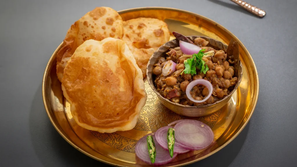 Crispy bhature with spicy chole curry - iconic Delhi street food served in a clay plate.