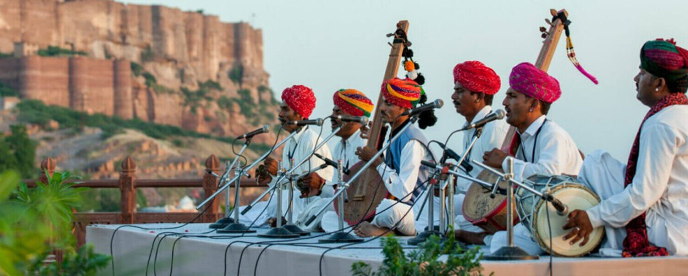 Elderly Garo musician playing 'chigring' string instrument while singing folk ballads in Tura, Meghalaya.