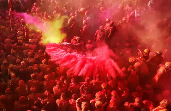 Holi festival in Delhi - crowds throwing colorful gulal powder at Connaught Place with music.