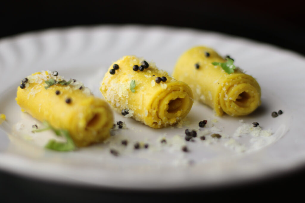Rolled Khandvi garnished with mustard seeds, a Gujarati delicacy.