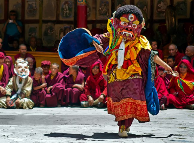Monks performing Cham dance in Ladakh wearing elaborate masks and robes.