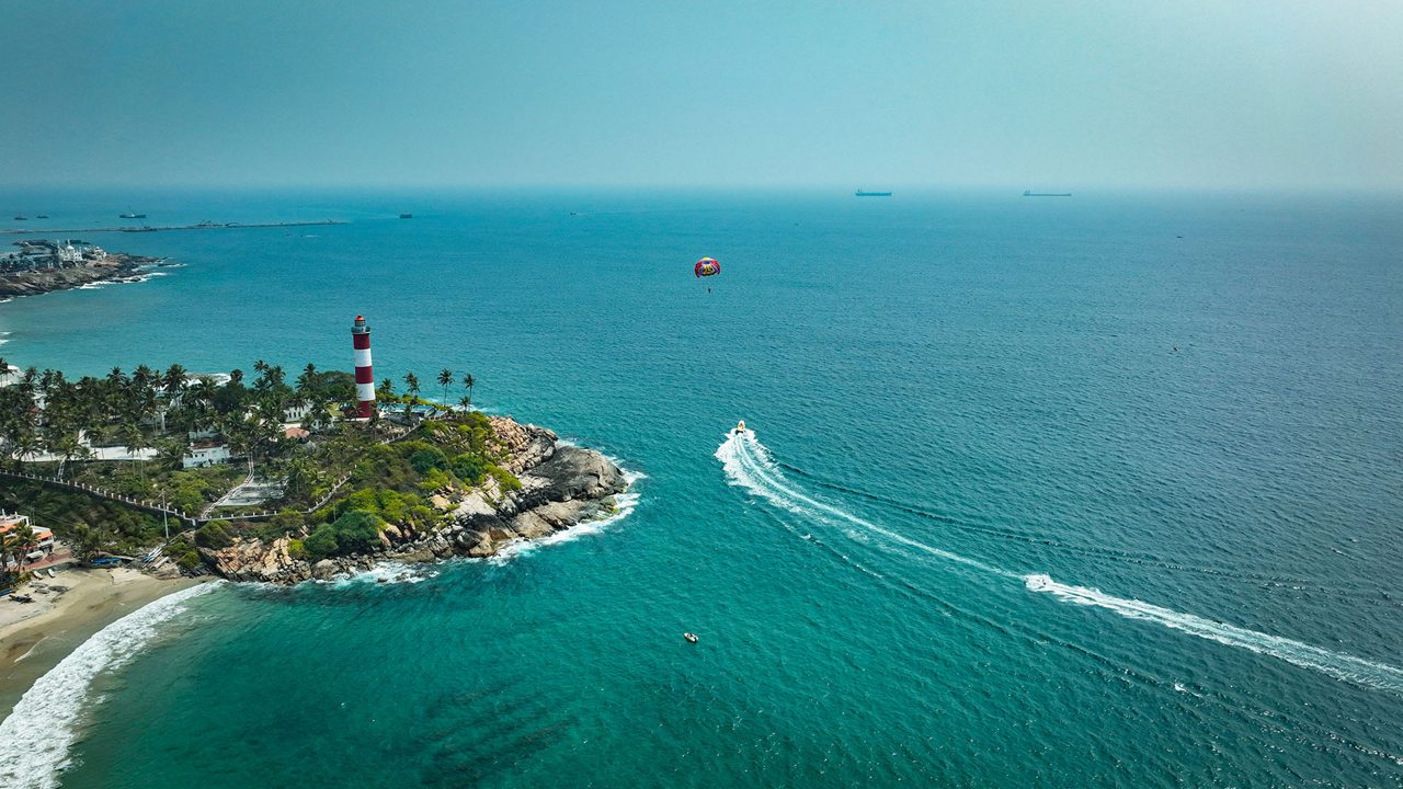 Tourists relaxing at the lighthouse beach in Kovalam, Kerala.