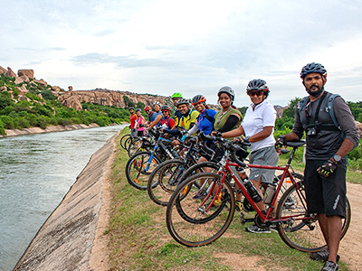 Tourist cycling past temples and ruins in Hampi