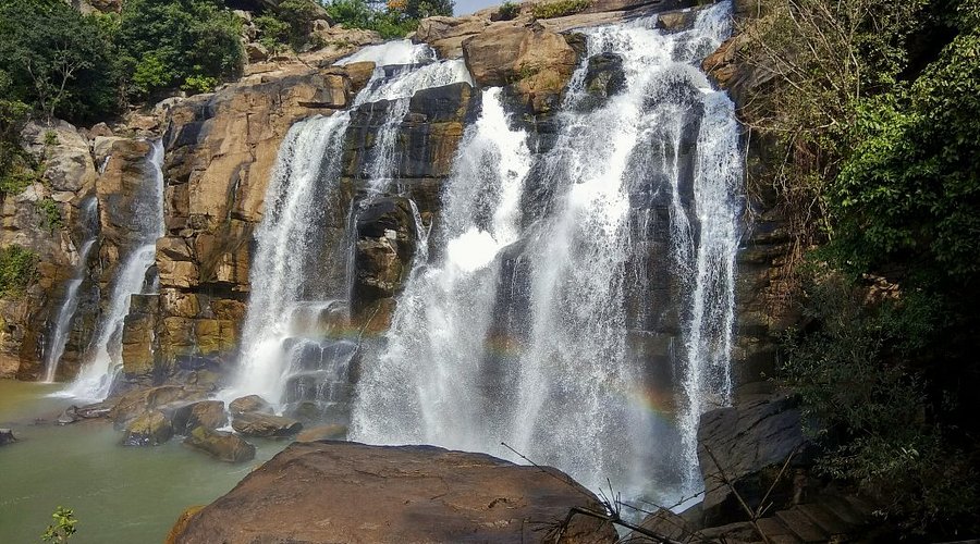 Jonha Falls cascading down rocky cliffs surrounded by forest