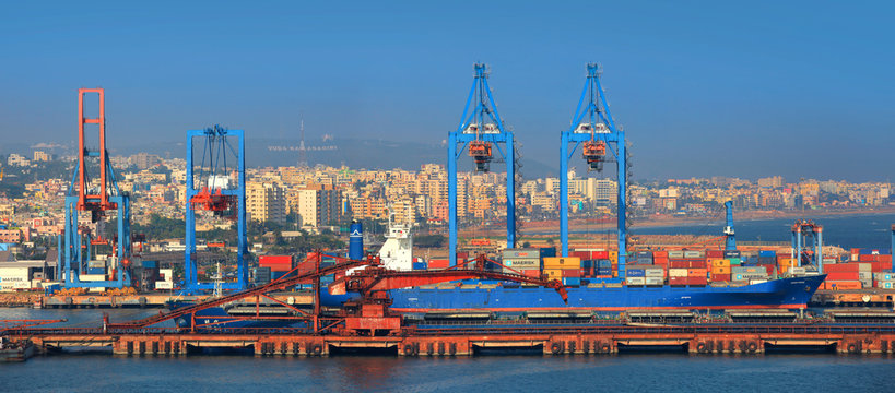 Aerial view of Visakhapatnam Port, one of India's largest and busiest harbors with cargo ships and cranes along the coastline.