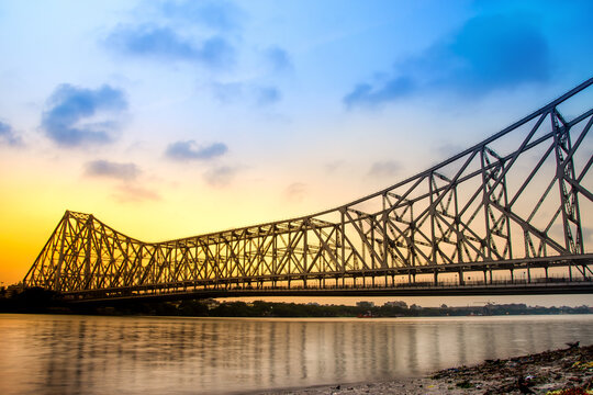 Iconic Howrah Bridge spanning the Hooghly River in Kolkata, with steel girders and bustling traffic.