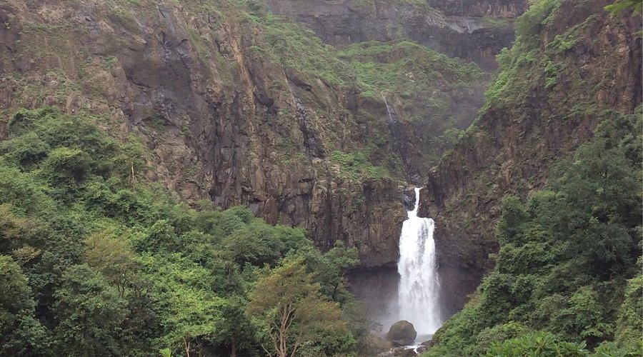 A waterfall cascading next to the ancient Marleshwar Temple, creating a scenic and spiritual setting.