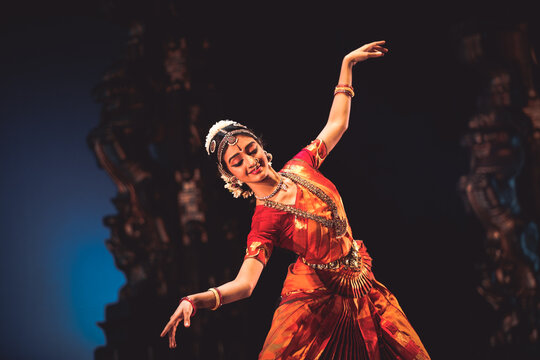 A Bharatanatyam dancer performing against the backdrop of ancient monuments in Mahabalipuram.