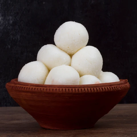 A bowl of white, spongy Bikaneri rasgullas soaked in sugar syrup.