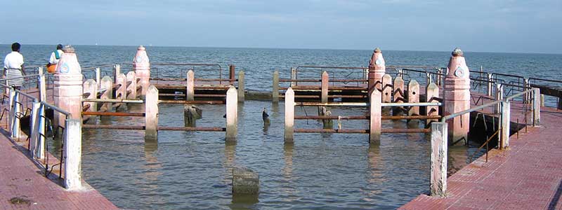 Nine stone idols submerged in the shallow waters of the beach at Devipattinam.