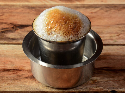 A traditional steel tumbler and davara filled with frothy South Indian filter coffee.