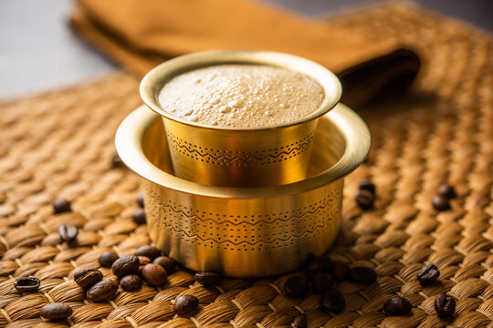 A traditional stainless steel tumbler and davara containing fresh, frothy Filter Coffee.