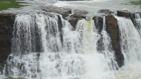 The powerful Gira Waterfalls cascading down a rocky cliff into a pool, surrounded by the dense green forests of Gujarat's Dang district.