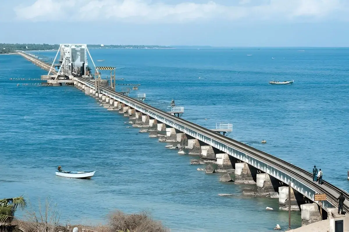 The iconic cantilever Pamban Bridge in Rameshwaram with a train passing over the blue sea.