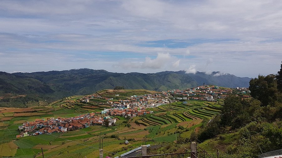 A panoramic view of the terraced garlic farms and traditional huts in Poombarai Village.
