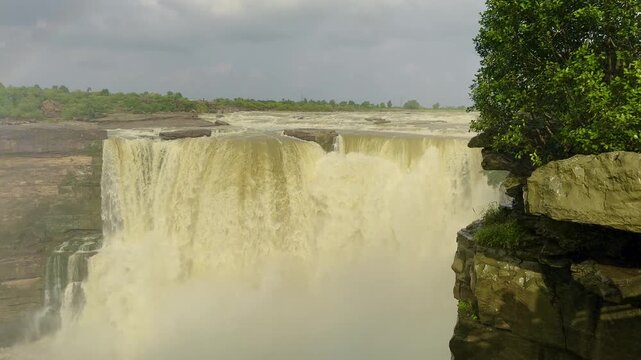 A wide, serene cascade of water flowing over layered rock steps into a calm pool, highlighting the diverse landscapes of Central India's Famous Waterfalls.