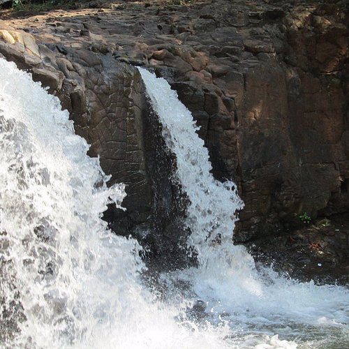 A gentle, sacred waterfall flowing over smooth rocks in a temple area near the source of the Narmada River.