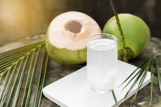 A vendor holding a large green tender coconut, ready to be opened for its refreshing water.