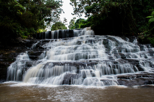 A small, charming waterfall known as Vattakanal Falls, flowing over mossy rocks.
