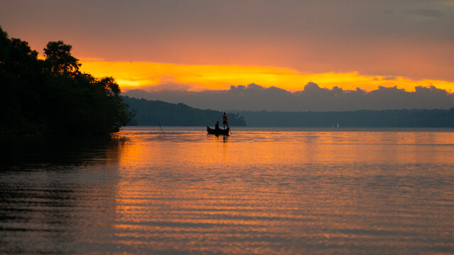 A serene backwater scene, a top place to visit in Kollam, with houseboats on Ashtamudi Lake.