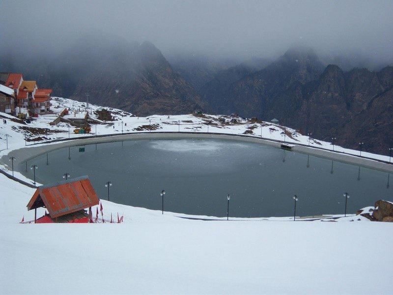 The serene, man-made Auli Artificial Lake reflecting snowy peaks, a key place to visit in Auli.