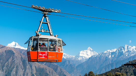 Gondola cabins of the Auli Ropeway, Asia's longest, traveling over lush slopes with panoramic Himalayan views.