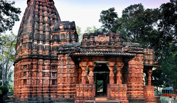 The stone-carved Bhoramdeo Temple, often called the Khajuraho of Chhattisgarh, features ornate erotic and divine sculptures on its outer walls, set against lush green hills.