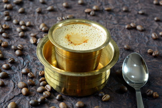 South Indian filter coffee being poured from a traditional stainless steel tumbler.