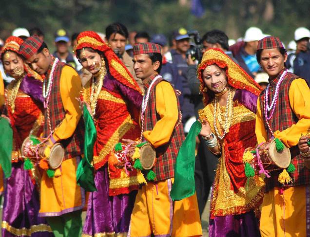 A group of dancers in traditional Garhwali attire performing a lively folk dance.