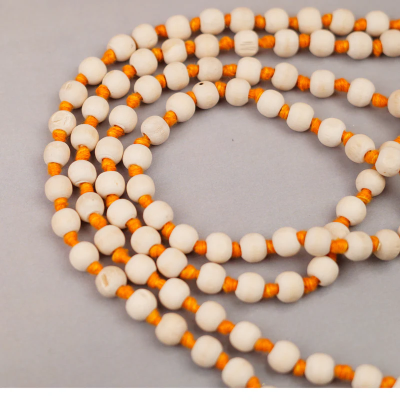 A small copper pot of Godavari Jal (holy water) next to a Tulsi bead mala (rosary).