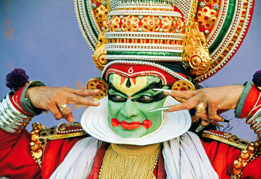 A Kathakali artist in elaborate costume and colorful makeup performing dramatic expressions.