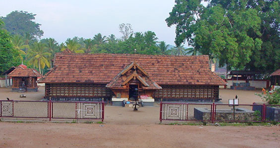 The traditional roof and entrance of the Kulathupuzha Sastha Temple amidst trees.