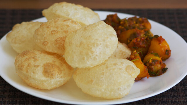 A traditional Bengali breakfast of fluffy luchi bread served with spicy alur torkari (potato curry).