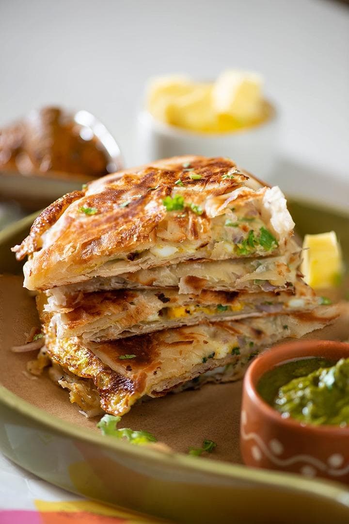 A crispy, golden-brown Moglai Paratha stuffed with spiced keema, served on a plate.