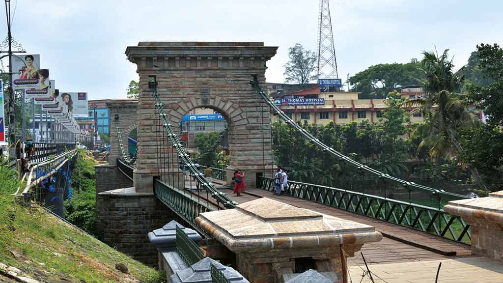 The iconic iron chains and structure of the historic Punalur Suspension Bridge.