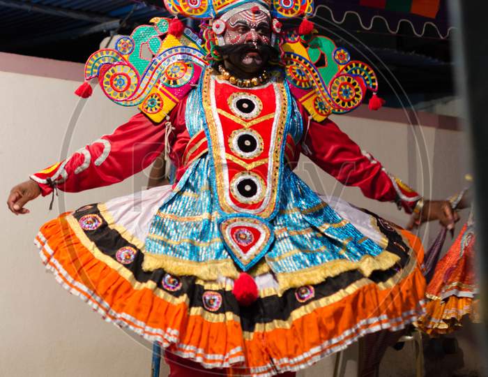 A street theater (Therukoothu) artist in colorful makeup and costume performing.
