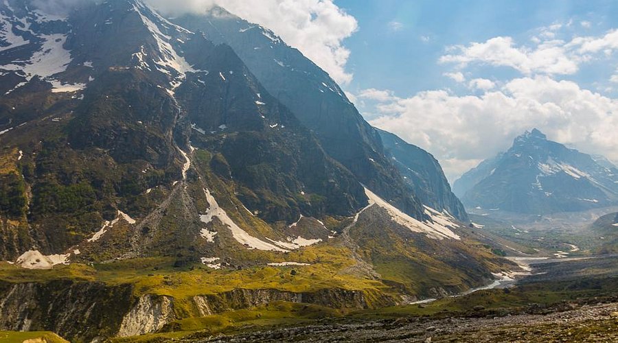 The tall, cascading white waters of Vasudhara Falls against a rocky mountainside.