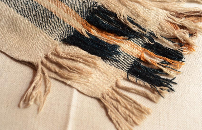 A stack of soft, handwoven woollen shawls in various colors.