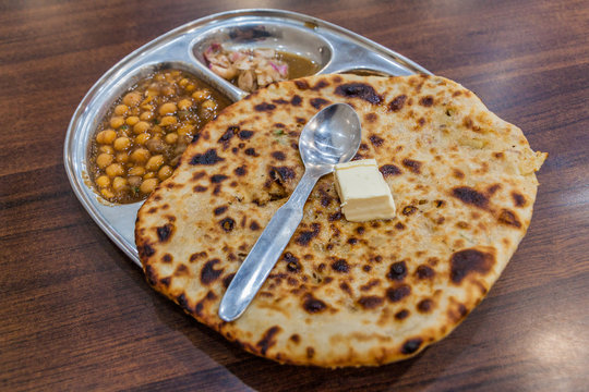 Crispy, flaky Amritsari Kulcha stuffed with spiced potatoes, served with chole and pickles.