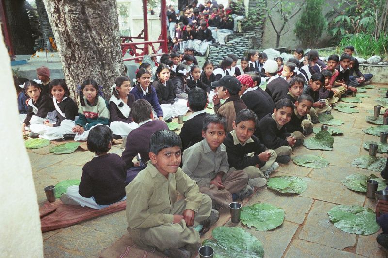 Rows of people sitting in pangat for a communal meal at a temple.