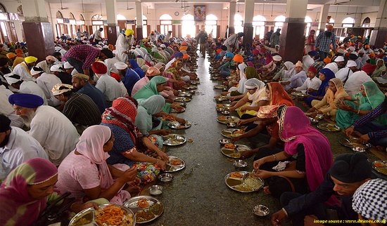 A Waza (master chef) serving guests from a large Trammi (copper plate) during a Wazwan feast.