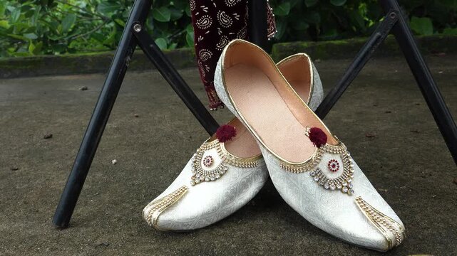 Traditional embroidered mojari shoes in golden thread, displayed at a Kota market stall.