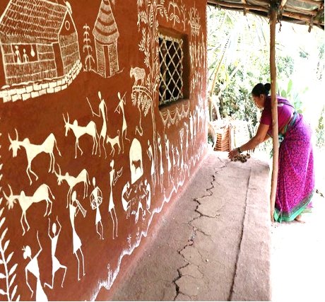 Traditional Warli tribal paintings depicting marriage rituals on a hut wall.