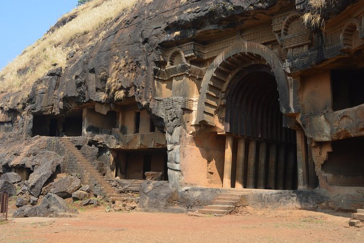 Close-up view of the detailed wooden architecture and stone carvings at the entrance of the Bhaja Caves.