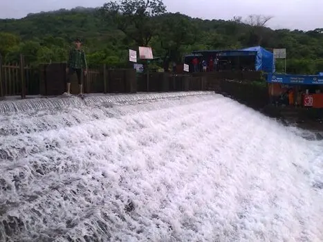 Tourists enjoying waterfall wading at Bhushi Dam during monsoon, one of the top places to visit Khandala for family fun.