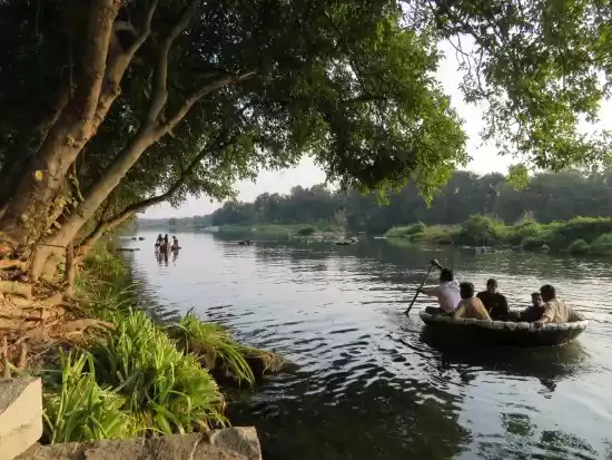 Tourists enjoying a peaceful boat ride on the holy Kaveri River flowing through Tiruchirappalli.