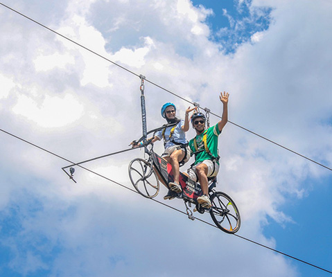 Adventure seekers zip-lining through scenic mountain landscapes at Della Adventures.