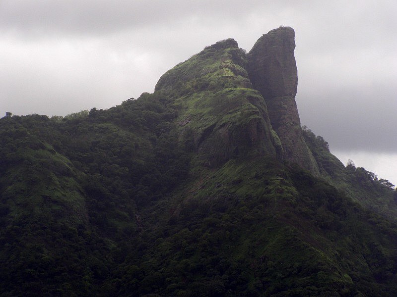 The iconic cliff of Duke's Nose standing tall against a blue sky, a famous trekking destination in Khandala offering panoramic views.