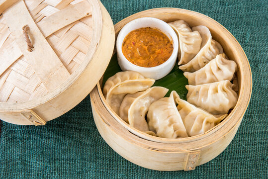 Plate of freshly steamed vegetable and chicken momos with dipping sauce.